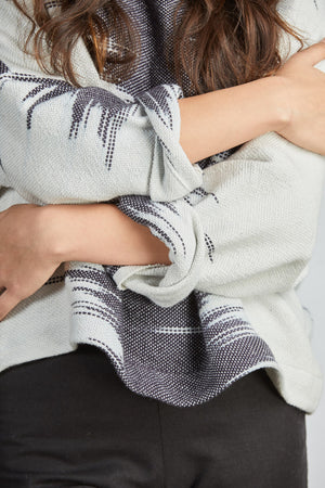 woman wearing a blue and white patterned hand woven oversized sweater with black pants