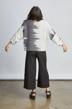 woman wearing a blue and white patterned hand woven oversized sweater with black pants