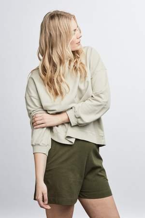 woman wearing green raw silk noil high waisted shorts and white tee shirt