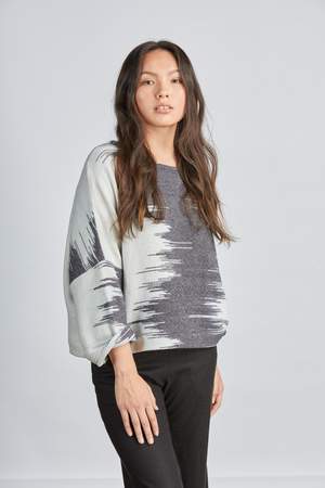 woman wearing a blue and white patterned hand woven oversized sweater with black pants