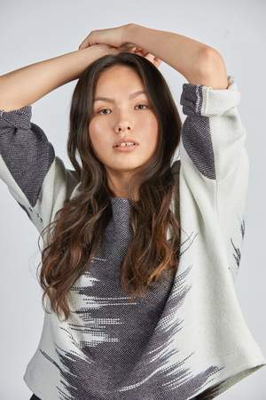 woman wearing a blue and white patterned hand woven oversized sweater with black pants