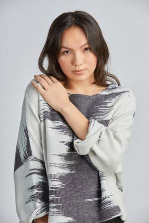 woman wearing a blue and white patterned hand woven oversized sweater with black pants