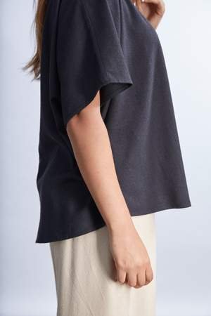 model wearing a white flowy raw silk noil blouse and black pants