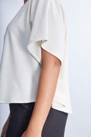 model wearing a white flowy raw silk noil blouse and black pants